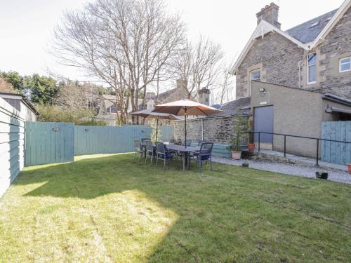 a patio with a table and an umbrella in a yard at Glenspey in Kingussie