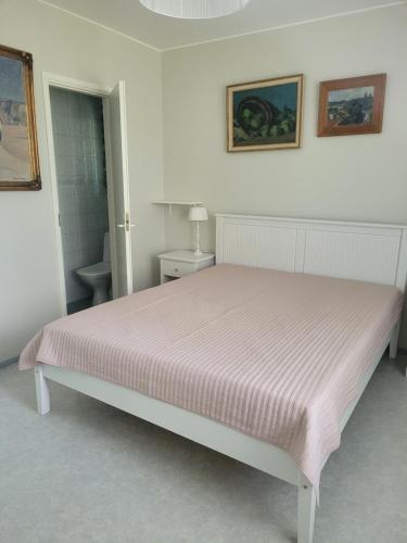 Un dormitorio blanco con una cama con una manta rosa. en Blue villa with private beach, en Kesälahti