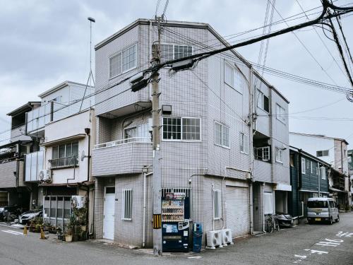 a tall white building on the side of a street at 大正車站4分陽当たり良い貸切一軒家 in Osaka