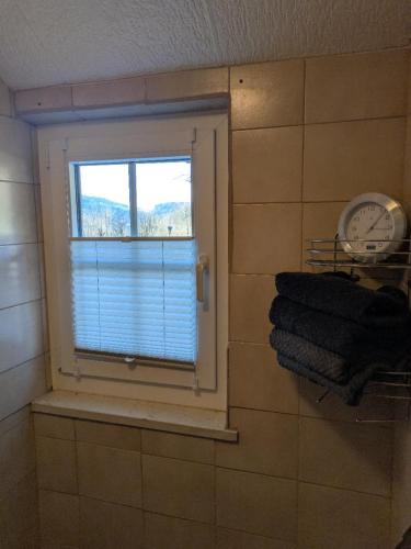 a window in a bathroom with a clock and towels at Haus Bärnstein in Grafenau