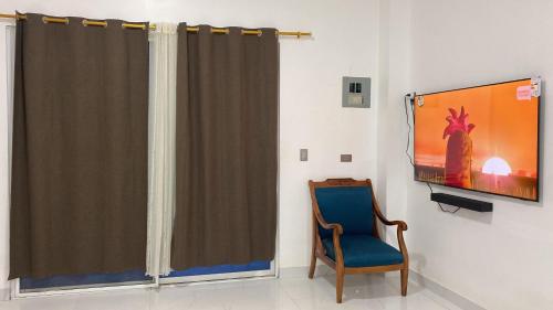 a room with a curtain and a tv and a chair at Apartamento Ciudad del Surf Montañita in Montañita
