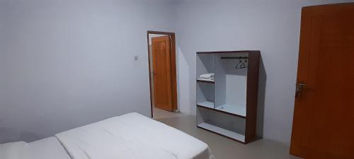 a white room with a bed and a mirror at Renny's Tangkoko Safety Stop in Bitung