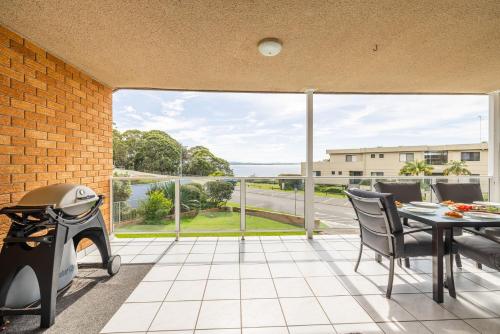 a patio with a table and chairs and a view of the ocean at Portofino, 1,7 Laman Street - First floor unit with beautiful views, air con and Wi-Fi and close to town in Nelson Bay