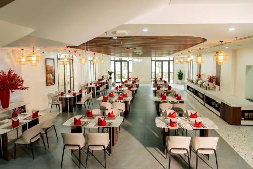 a restaurant with tables and chairs with red flowers on them at Belliss Hotel And Spa Dai Lai in Phúc Yên