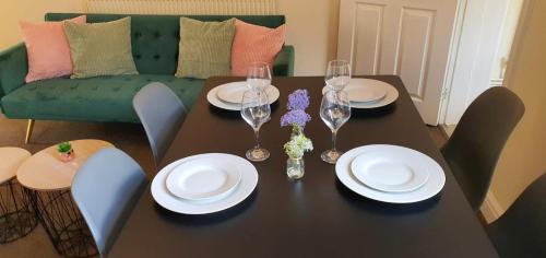 a dining room table with plates and wine glasses at Victoria House in Stoke on Trent