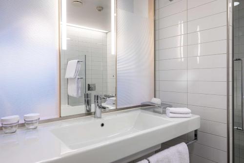 a white bathroom with a sink and a mirror at Hilton Helsinki Airport in Vantaa