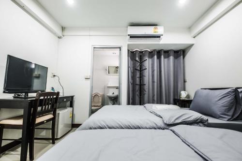a bedroom with two beds and a desk and a television at Don Muang Hotel in Bangkok