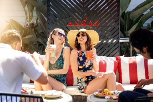 two women in swim suits sitting on a couch with drinks at Andaz San Diego, By Hyatt in San Diego