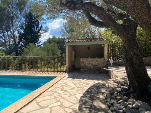 une piscine avec un arbre et un bâtiment dans l'établissement Cocon de Provence, au Cannet-des-Maures