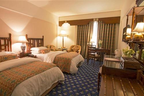 a hotel room with two beds and a desk at Faisalabad Serena Hotel in Faisalabad
