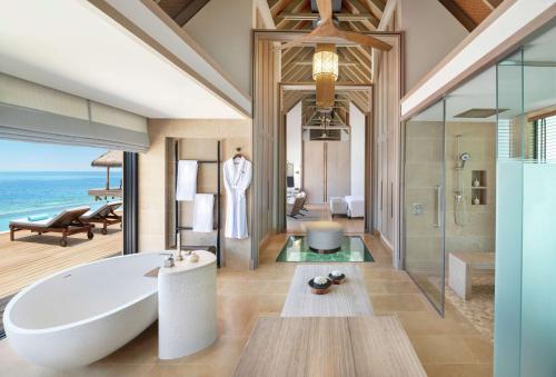 a bathroom with a tub and a shower with the ocean at Waldorf Astoria Maldives Ithaafushi in South Male Atoll