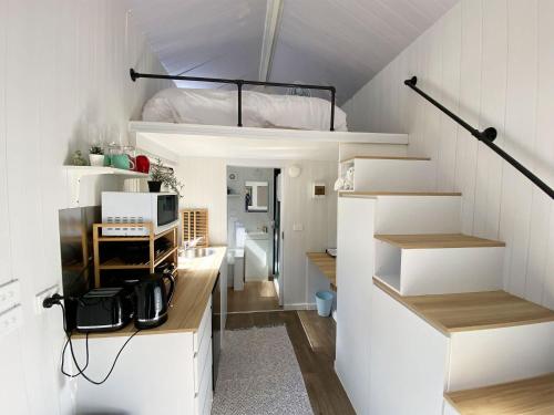 a white room with a loft bed and a kitchen at Celestial Haven by Tiny Away in Toolangi