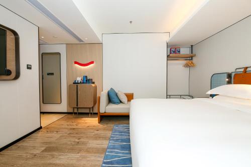 a bedroom with a bed and a living room at Echarm International Hotel Guangzhou South Railway Station Zhongcun Metro Station Branch - Free Shuttle Bus to Canton Fair Complex During Canton Fair Period & Free Deliver Service to Guangzhou Baiyun International Airport in Guangzhou