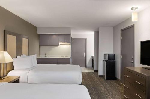 a hotel room with two beds and a television at Baymont by Wyndham Moses Lake in Moses Lake
