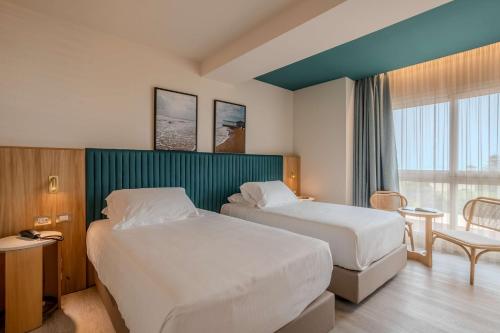 a hotel room with two beds and a window at Terradamari Resort & Spa Marina di Modica,Tapestry by Hilton in Marina di Modica