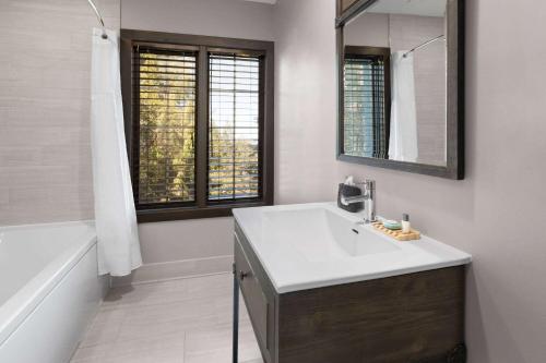 a bathroom with a sink and a mirror and a tub at Corduroy Inn and Lodge, Trademark Collection by Wyndham in Snowshoe