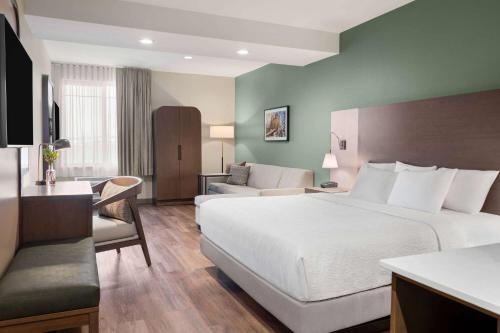 a hotel room with a large bed and a couch at La Quinta Inn and Suites by Wyndham Lincoln in Lincoln