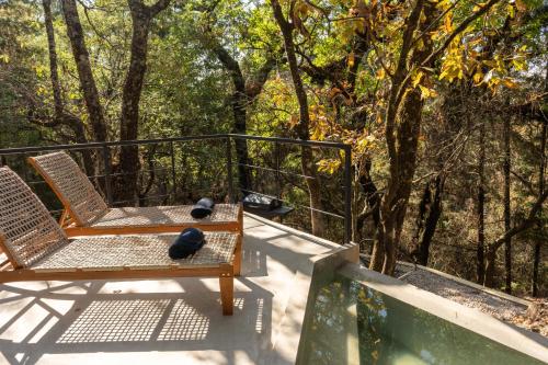 two chairs on a porch with trees in the background at Grasshopper Cabañas in Cuautla Morelos