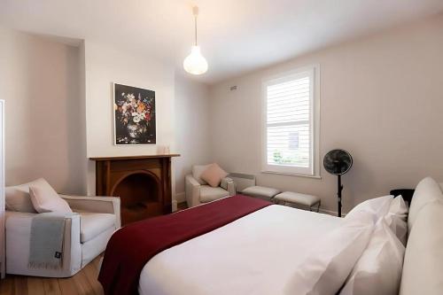 a white bedroom with a bed and a chair at 'Sobrina=' - A home away from home in Sandy Bay in Sandy Bay