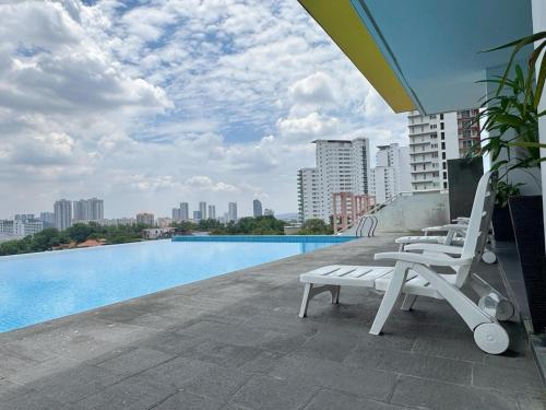 a row of lounge chairs sitting on the edge of a swimming pool at Comfy Studio Neo Damansara Ikea Ikano 2Pax1CP in Petaling Jaya