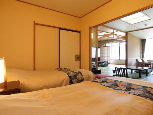 南伊豆町にあるホテル河内屋のベッド2台とテーブルがあるホテルの部屋