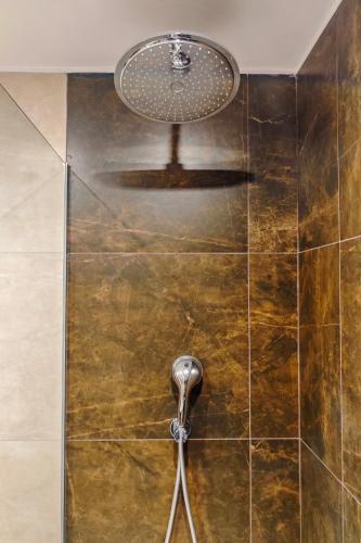 a shower with a shower head on a tiled wall at Casa Maisie Apartment in Burgau