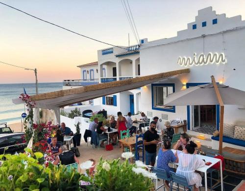um grupo de pessoas sentadas em um restaurante ao lado do oceano em Casa Maisie Apartment no Burgau