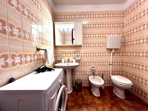 a bathroom with a sink and a toilet and a mirror at Blue wave apartment by the sea in Lignano Sabbiadoro