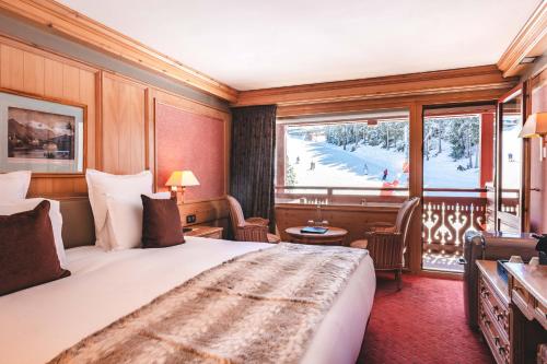a hotel room with a large bed and a balcony at Hotel Carlina in Courchevel
