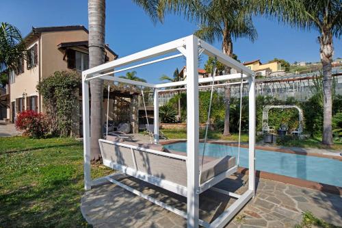a white pergola next to a swimming pool at Villa Vallegrande in Ospedaletti