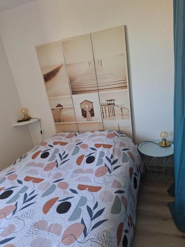 ein Schlafzimmer mit einem Bett mit geblümter Tagesdecke in der Unterkunft appartement T2bis idealement situé au bord du lac marin de Vieux Boucau in Vieux-Boucau-les-Bains