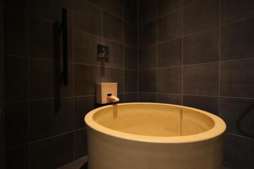 a bath tub in a bathroom with black tiles at Arima Kirari in Kobe