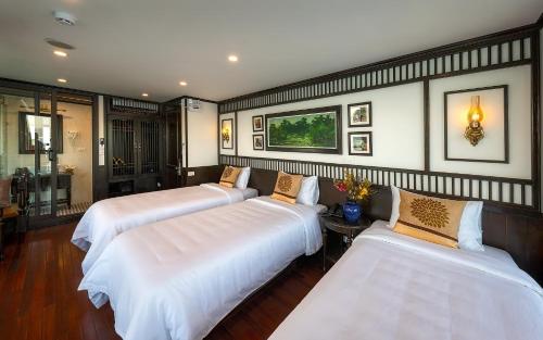 a bedroom with three beds with white sheets at Sena Cruises - Wonder On Lan Ha Bay in Ha Long
