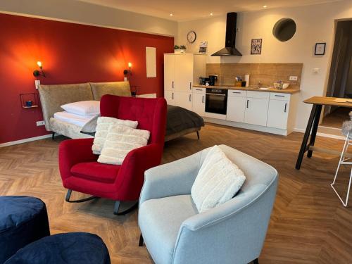a living room with a red chair and a bed at #8 Ommi Kese See-Suite FD Sauna Hund Terrasse in Olpe