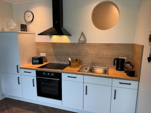 a kitchen with white cabinets and a sink and a clock at #8 Ommi Kese See-Suite FD Sauna Hund Terrasse in Olpe