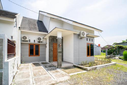a small white house with orange doors at Griya Godean Homestay Jogja in Godean