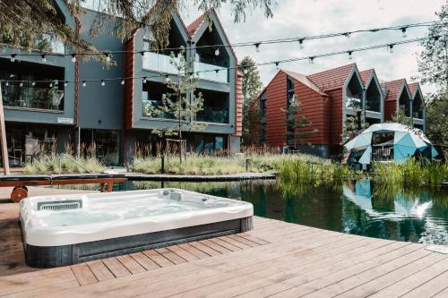 a bath tub sitting on a wooden deck next to a body of water at Hill Palanga & SPA in Palanga