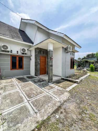 a small white house with a driveway at Griya Godean Homestay Jogja in Godean