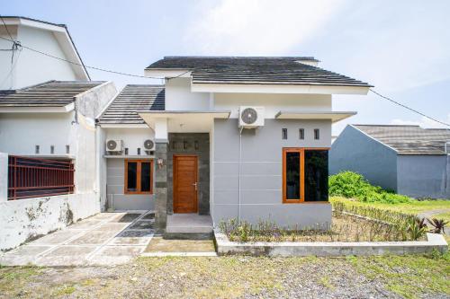 a white house with a brown door at Griya Godean Homestay Jogja in Godean