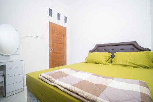 a bedroom with a bed with yellow pillows at Griya Godean Homestay Jogja in Godean