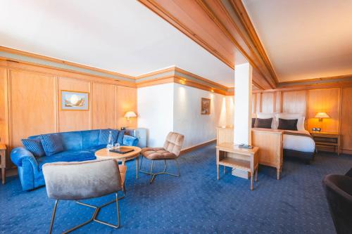 a hotel room with a blue couch and a bed at Hotel Carlina in Courchevel
