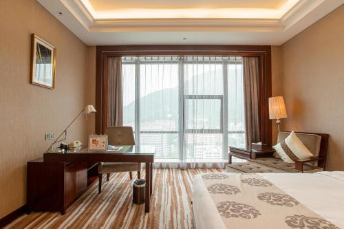 a hotel room with a desk and a bed and a window at Wyndham Grand Plaza Royale Chenzhou in Chenzhou