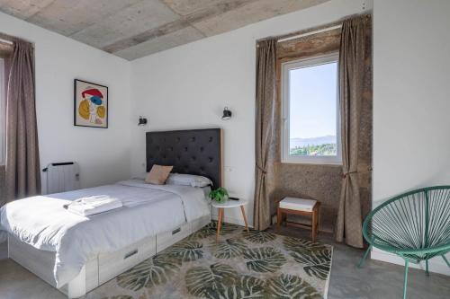 a bedroom with a bed and a chair and a window at Casa Cándido in Ribarteme