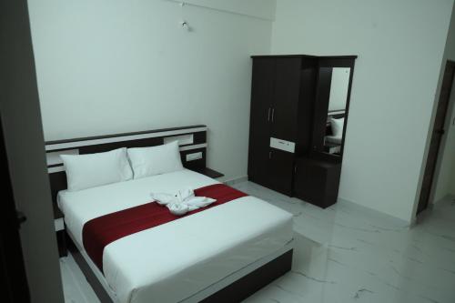 a bedroom with a white bed and a black cabinet at CAT'S EYE Hotel in Cochin