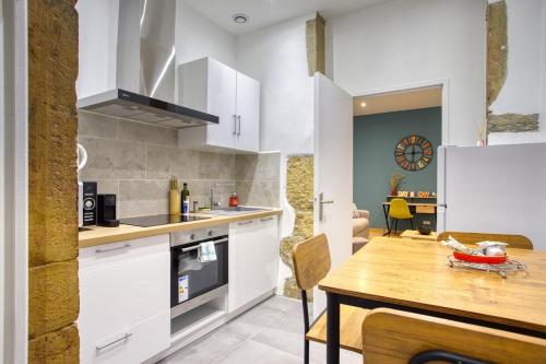 une cuisine avec des armoires blanches et une table en bois dans l'établissement Superbe, rénové, hyper centre, à Lyon