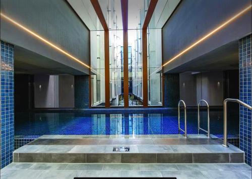 a large swimming pool with blue tiles and a building at 112 at Plush Midnight in Canberra