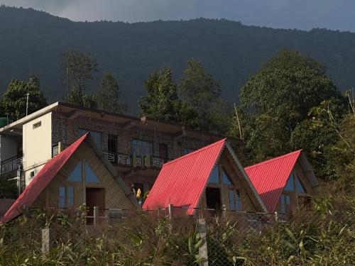 a house with red roofs in front of a mountain at Khee Homestay in Kurseong