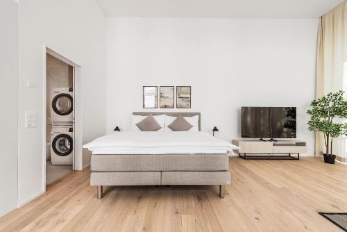 a white bedroom with a bed and a flat screen tv at DESIGN-STUDIO 1 !Gratis Parken, Free Parking! in Kreuzlingen