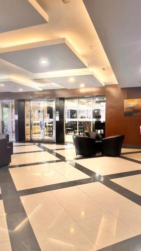 a lobby with a waiting area with chairs and tables at Hotel Seri Malaysia Kepala Batas in Kepala Batas