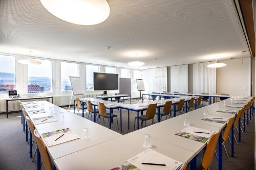 a conference room with tables and chairs and a screen at Le Domaine (Swiss Lodge) in Fribourg